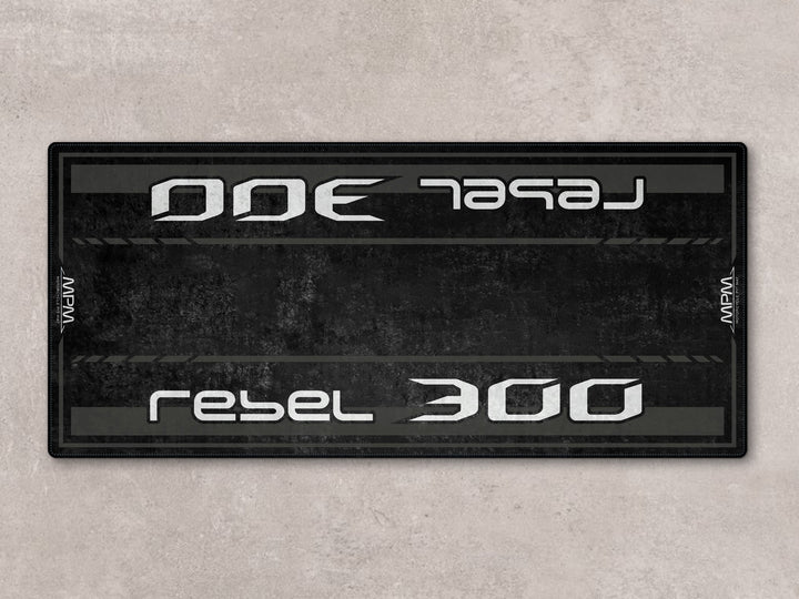 Rebel 300 pit mat in black. Durable floor cover and parking mat ideal for garage setups and daily rider use.