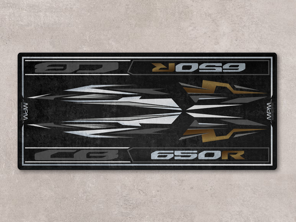Matte gray and gold pit mat for CB650R. High-performance floor cover for racetrack prep, parts zone, or motorcycle gear area.