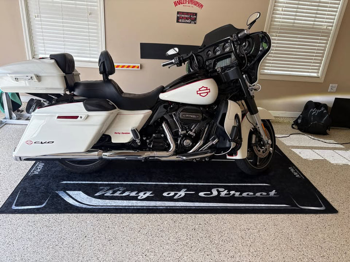 Harley Davidson motorcycle on a 'King of the Street' mat in a room with a window and wall decor.