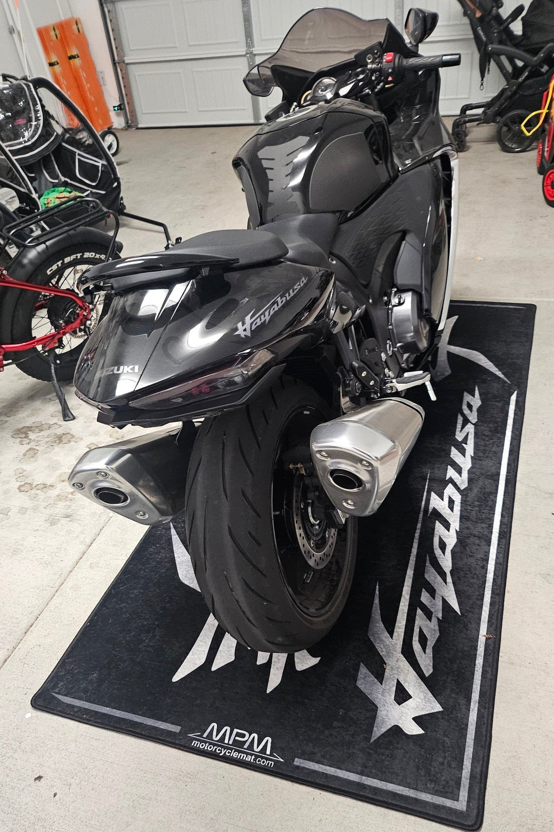 Suzuki Hayabusa on custom motorcycle pit mat in indoor garage, non-slip floor cover for hyperbike display.